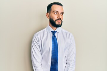 Young man with beard wearing business tie smiling looking to the side and staring away thinking.