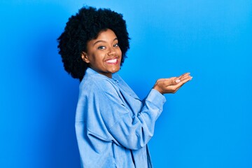 Young african american woman wearing casual clothes pointing aside with hands open palms showing copy space, presenting advertisement smiling excited happy