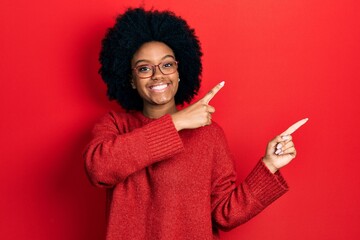 Young african american woman wearing casual clothes and glasses smiling and looking at the camera pointing with two hands and fingers to the side.