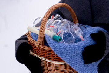 A woman in a gray coat holds a basket of hijama cans. Hijama jars and hijama pump, bloodletting, Chinese medicine