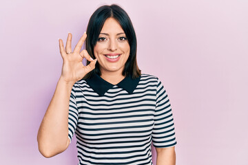Obraz na płótnie Canvas Young hispanic woman wearing casual clothes smiling positive doing ok sign with hand and fingers. successful expression.