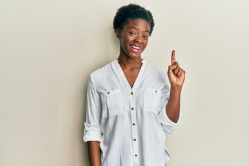 Young african american girl wearing casual clothes pointing finger up with successful idea. exited and happy. number one.