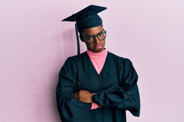 Young african american girl wearing graduation cap and ceremony robe skeptic and nervous, disapproving expression on face with crossed arms. negative person.