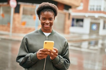 Young african american girl smiling happy using smartphone at the city