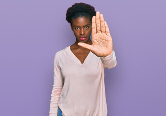 Young african american girl wearing casual clothes doing stop sing with palm of the hand. warning expression with negative and serious gesture on the face.