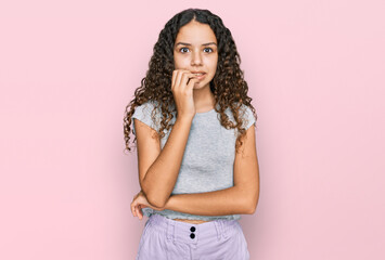 Teenager hispanic girl wearing casual clothes looking stressed and nervous with hands on mouth biting nails. anxiety problem.