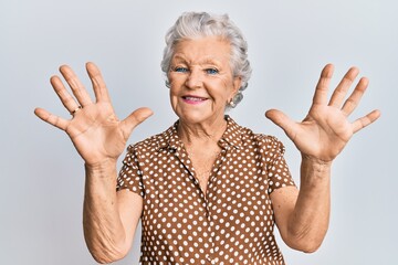 Senior grey-haired woman wearing casual clothes showing and pointing up with fingers number ten while smiling confident and happy.