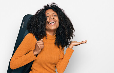 Young african american girl wearing guitar case celebrating victory with happy smile and winner...