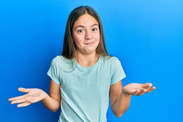 Beautiful brunette little girl wearing casual white t shirt clueless and confused expression with...