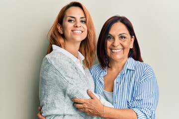 Latin mother and daughter wearing casual clothes looking positive and happy standing and smiling with a confident smile showing teeth
