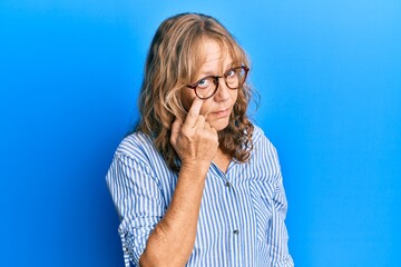 Middle age blonde woman wearing casual clothes and glasses pointing to the eye watching you...