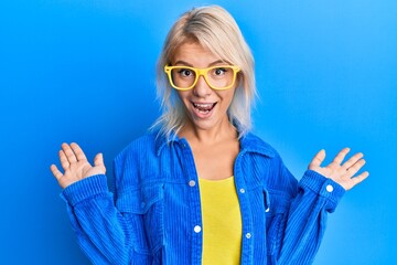 Young blonde girl wearing casual clothes and glasses celebrating victory with happy smile and...