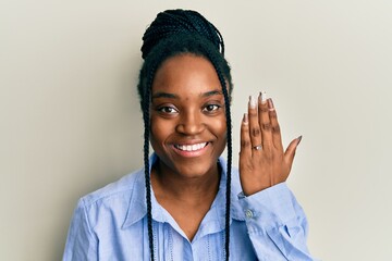 African american woman with braided hair wearing engagement ring looking positive and happy...
