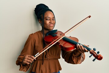 African american woman with braided hair playing violin skeptic and nervous, frowning upset because...