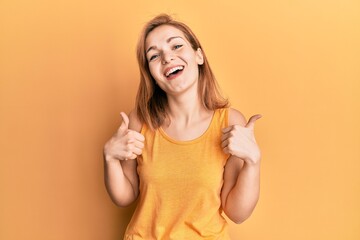 Young caucasian woman wearing casual style with sleeveless shirt success sign doing positive gesture with hand, thumbs up smiling and happy. cheerful expression and winner gesture.