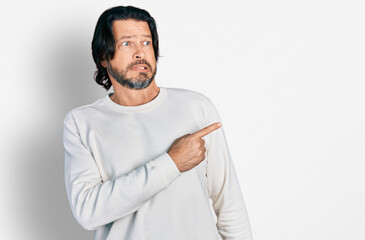 Middle age caucasian man wearing casual clothes pointing aside worried and nervous with forefinger,...