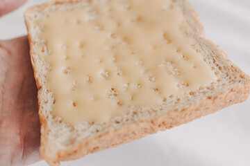 Hand holding bread with sweetened condensed milk on top. Easy dessert.