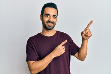 Fototapeta premium Young hispanic man wearing casual clothes smiling and looking at the camera pointing with two hands and fingers to the side.