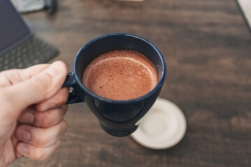 Close up of hand holding a cup of hot cocoa in a cafe.