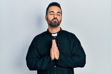 Handsome hispanic priest man with beard standing over isolated background looking at the camera...