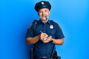 Middle age handsome man wearing police uniform writing traffic fine celebrating crazy and amazed for success with open eyes screaming excited.