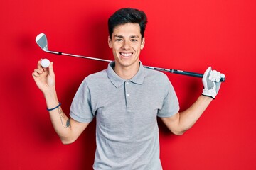Young hispanic man holding golf ball smiling with a happy and cool smile on face. showing teeth.