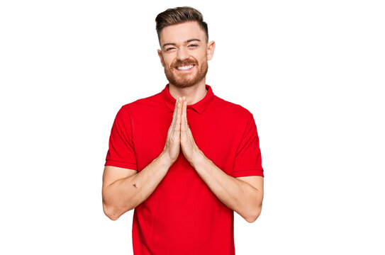 Young redhead man wearing casual clothes praying with hands together asking for forgiveness smiling confident.