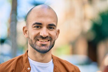 Fototapeta premium Young hispanic bald man smiling happy standing at the city.