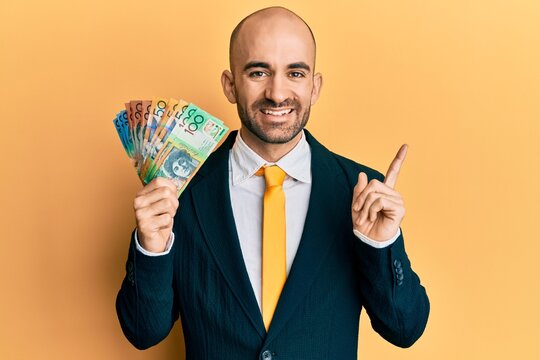 Young hispanic business man holding canadian dollars smiling happy pointing with hand and finger to the side