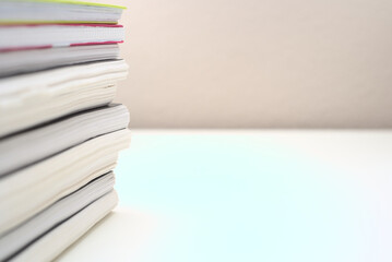 Stack of framed notes and books to study on a white table with bokeh background and copy space