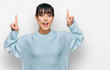 Young hispanic woman wearing casual clothes smiling amazed and surprised and pointing up with fingers and raised arms.