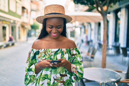 Young african american tourist woman on vacation smiling happy using smartphone at the city.