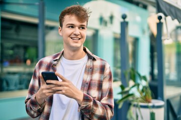 Young caucasian man smiling happy using smartphone at the city.