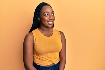 Young african american woman wearing casual clothes looking away to side with smile on face, natural expression. laughing confident.