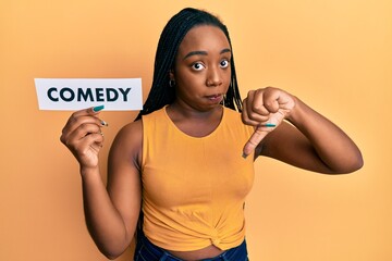 Young african american woman holding comedy word paper with angry face, negative sign showing...