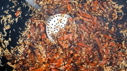Texture of the finished pilaf in the cauldron. Tasty pilaf is cooked on the street in a large cauldron. Street food concept.