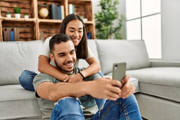 Obraz premium Young latin couple smiling happy making selfie by the smartphone at home.