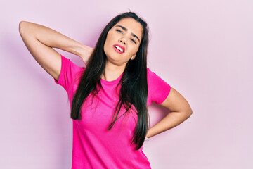 Young hispanic girl wearing casual pink t shirt suffering of neck ache injury, touching neck with hand, muscular pain