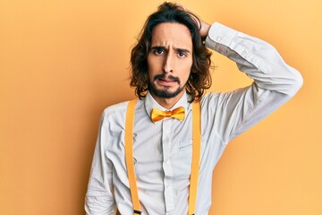 Young hispanic man wearing hipster elegant look confuse and wonder about question. uncertain with doubt, thinking with hand on head. pensive concept.