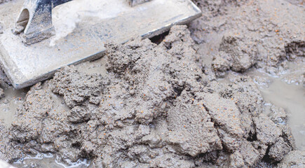 Cimento, Concreto. Carrinho de mão com mistura de cimento e areia e uma desempenadeira. Fotografia...
