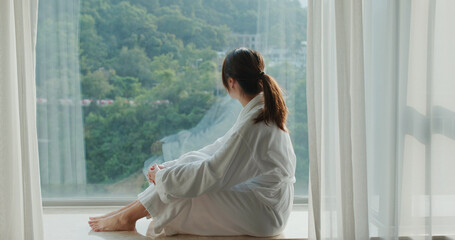 Woman look outside the window at hotel room - obrazy, fototapety, plakaty