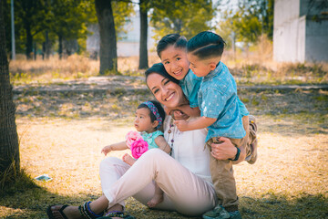 Mamá mexicana jugando con sus tres hijos en un parque