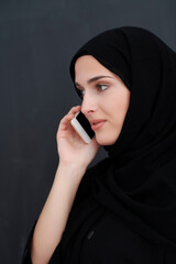 Young muslim businesswoman in traditional clothes or abaya talking on the smartphone