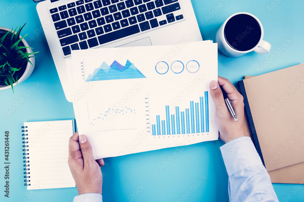 Poster hand of businessman holding documents report statistic financial with graph and chart and laptop com