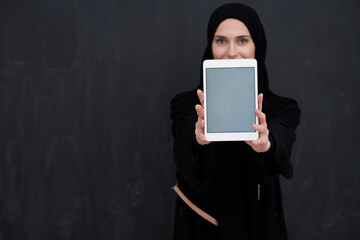 Young Arab businesswoman in traditional clothes or abaya holding tablet computer
