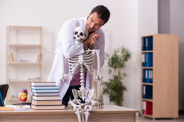 Young male doctor student studying human skeleton in the classroom