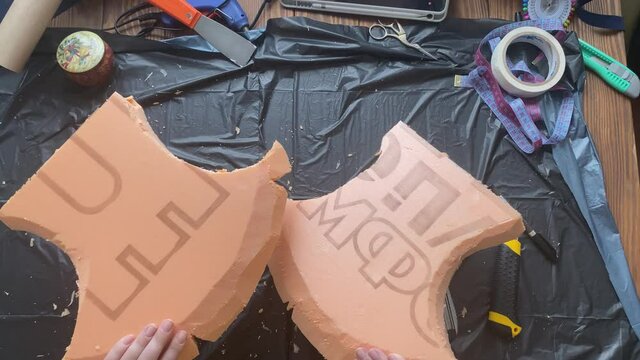 Two parts from homemade penoplex axe in women's hands. Diy cosplay costume. Creation of celtic or Viking hatchet.