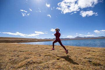 Woman trail runner cross country running on winter lakeside