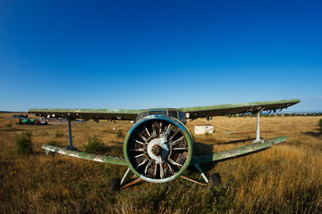 old plane stands in a field propeller close-up