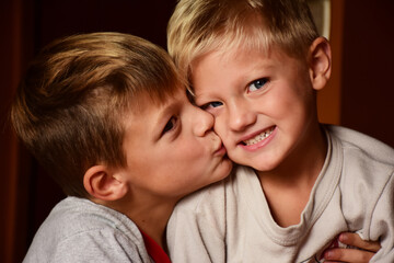 Closeup shot of a cheerful young Caucasian boy kissing his brother © Marisol Araujo/Wirestock